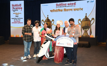 Kinetic awarding top performer at Firodia Karandak with electric scooter prize on stage